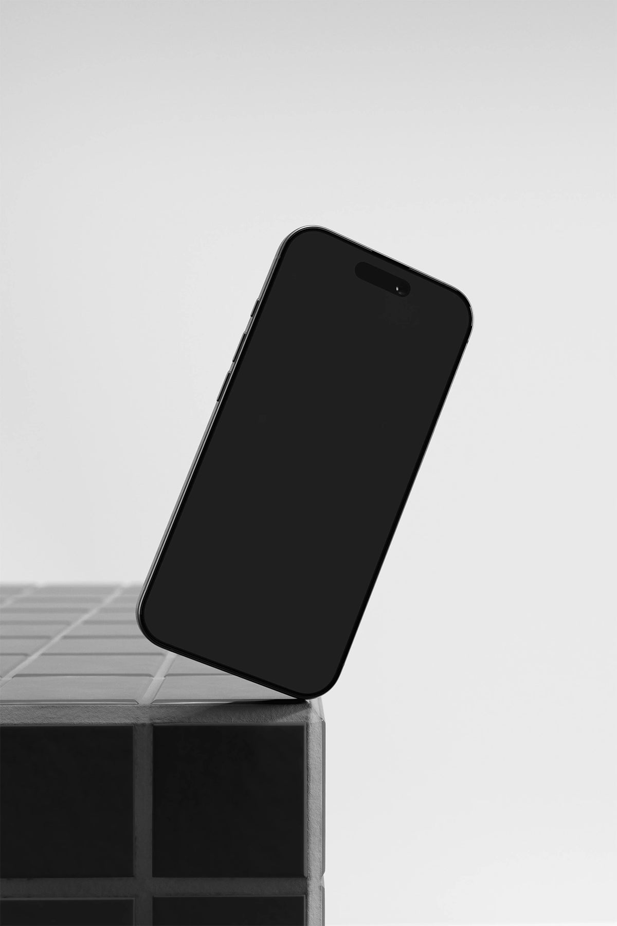 iPhone mockup on a gray tile table with a black UI placeholder for web and desktop UI presentation, angled view