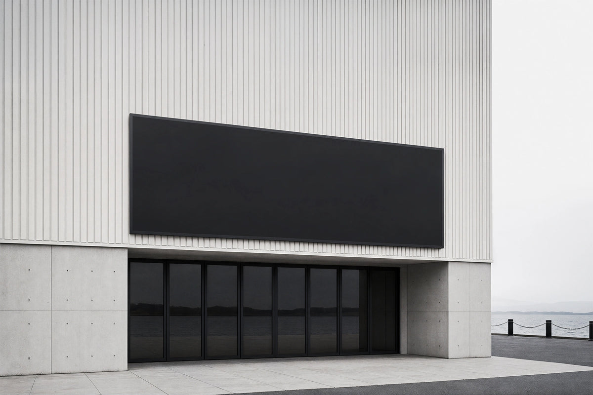 Digital billboard screen mockup with black placeholder mounted on the exterior of a modern gray building.